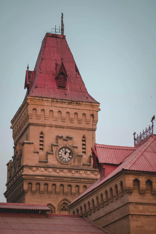 the clock tower is made from stone and has red roof tiles