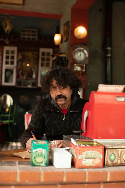 a man sitting at a table with a red toy stove