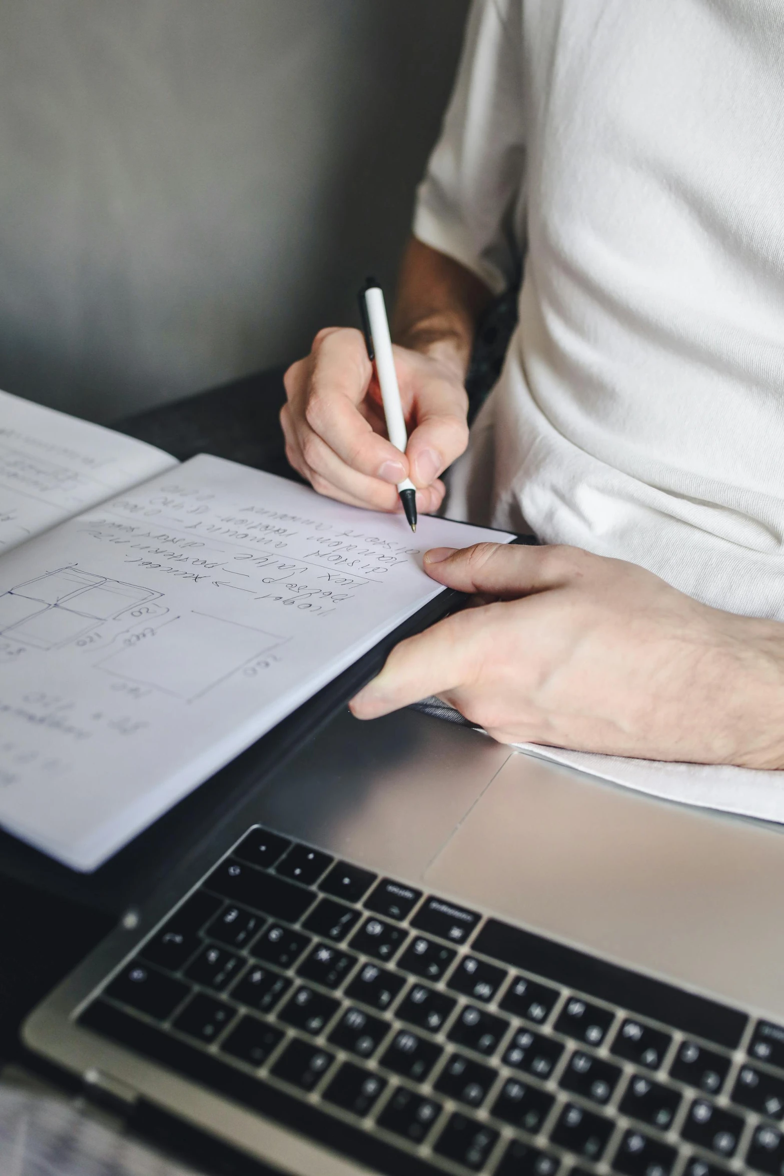 someone sitting at a desk taking notes on a sheet of paper