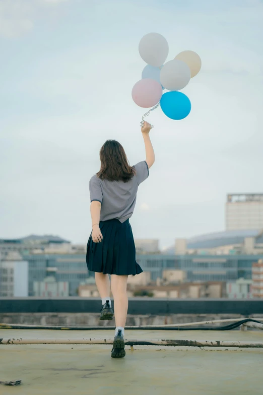 a woman is walking with several balloons up into the sky