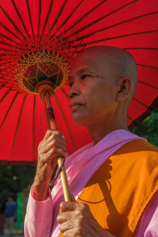 a man holding a red umbrella while standing next to other people