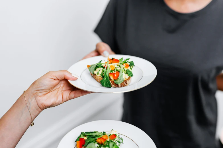 two women holding small plates of food in their hands