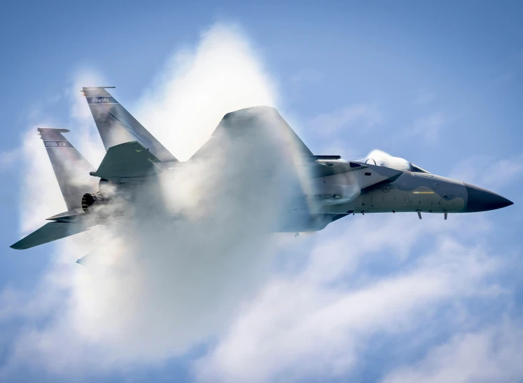 a fighter jet flying through the sky with clouds