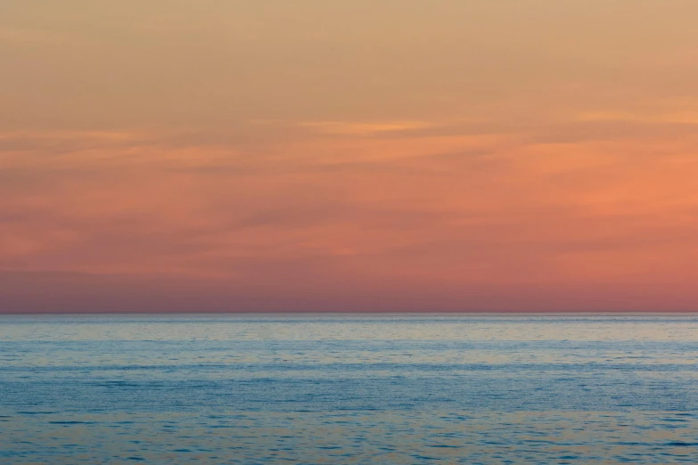 three people sit on the surfboard watching the sunset