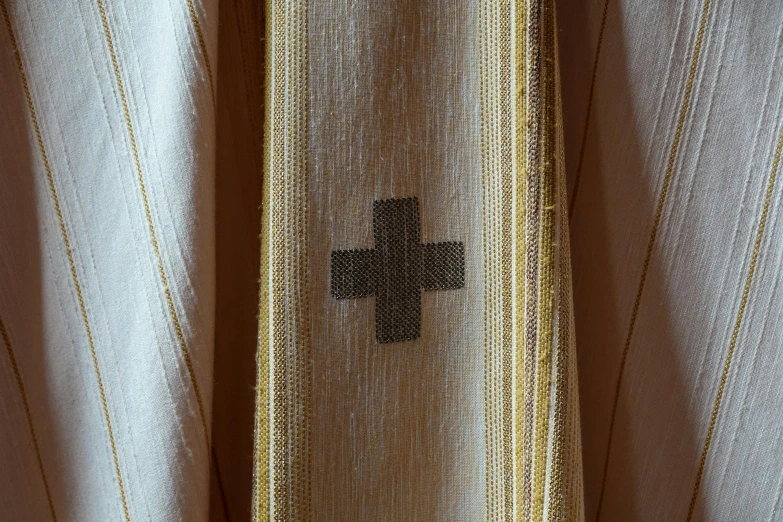 a cross is placed on the front of a sheer curtain