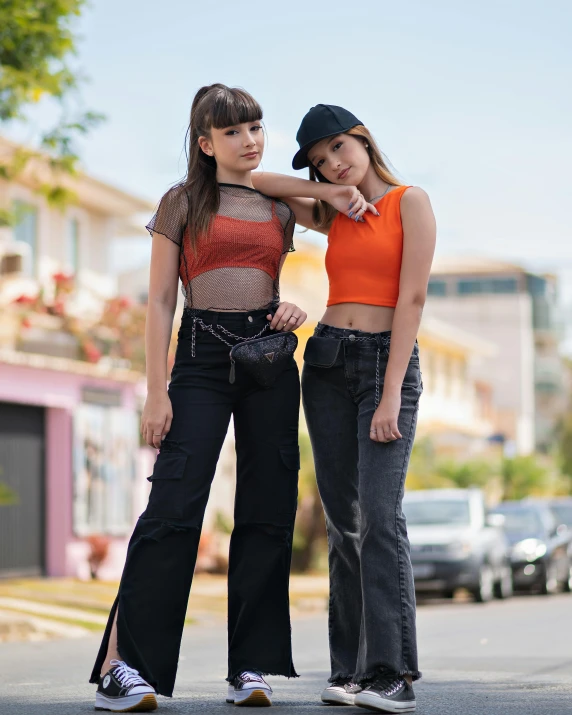two young women standing on the sidewalk wearing denims