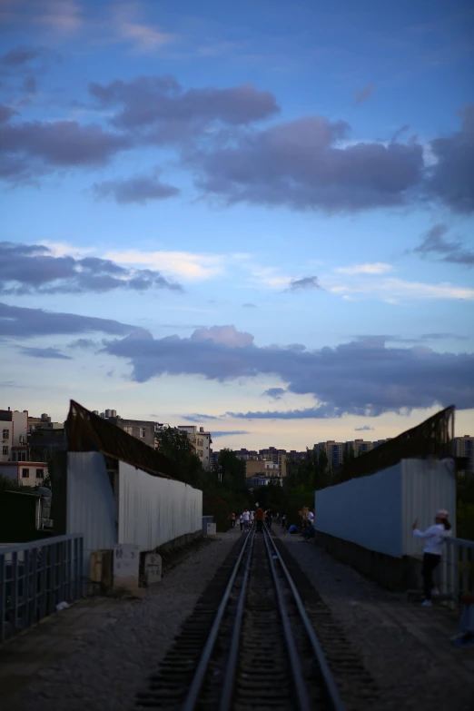 two people walking near the train tracks at dusk
