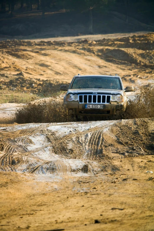 a jeep driving through a dirt road in a open field