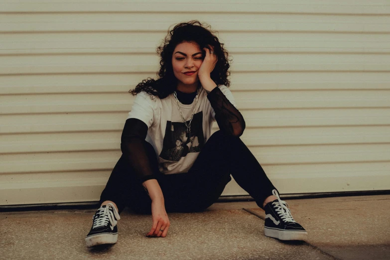 a young woman is sitting on the ground by a garage door