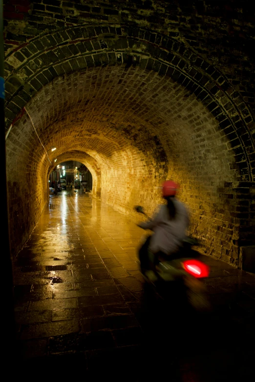 a man on a motorcycle rides through a tunnel