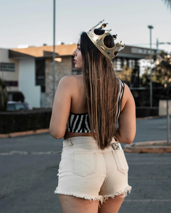 a woman in shorts is standing outside wearing a crown