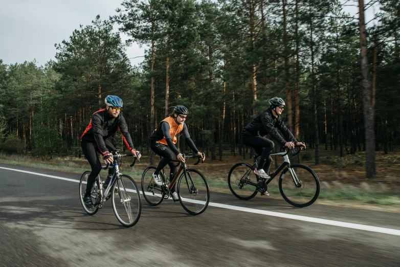 three people riding their bicycles on a road