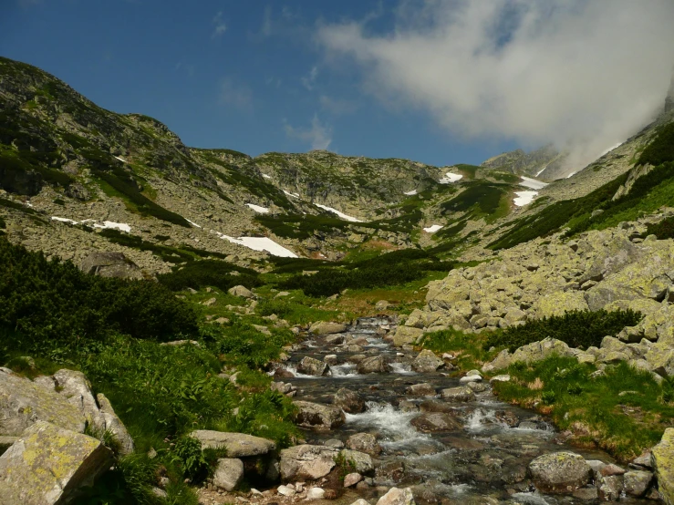 stream flowing between two large rocks and grassy valley