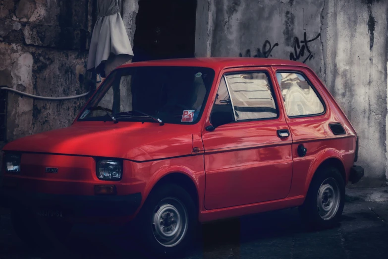 red car parked in front of an old wall