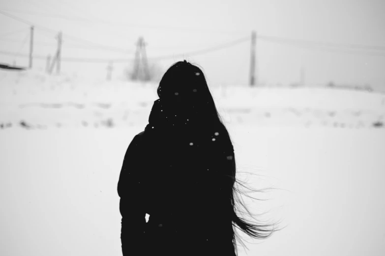 a person stands alone in the snow with long hair