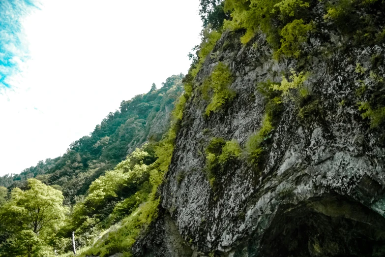 green mossy rock faces the road going down