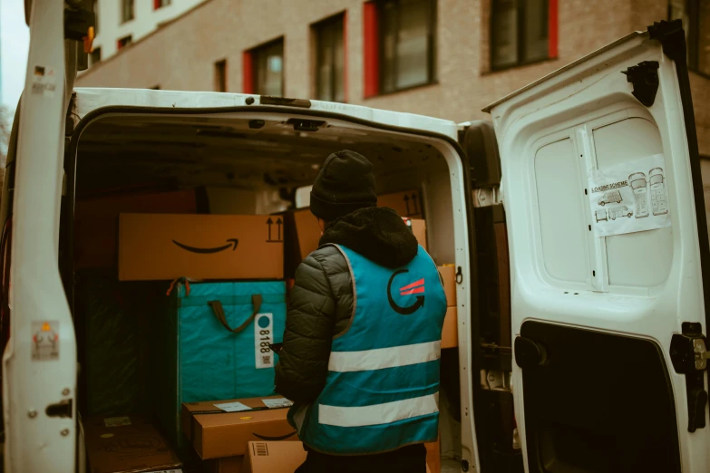 a man in a blue vest is walking towards an open van