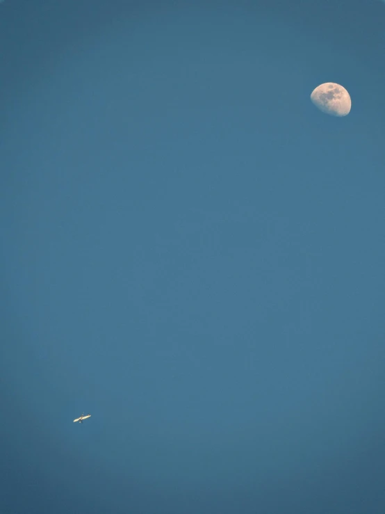 a plane flying by with the moon behind it