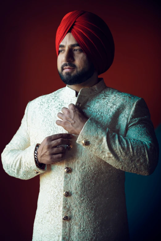 a man in a suit and turban adjusting his jacket