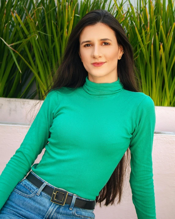 a woman is posing in front of some plants