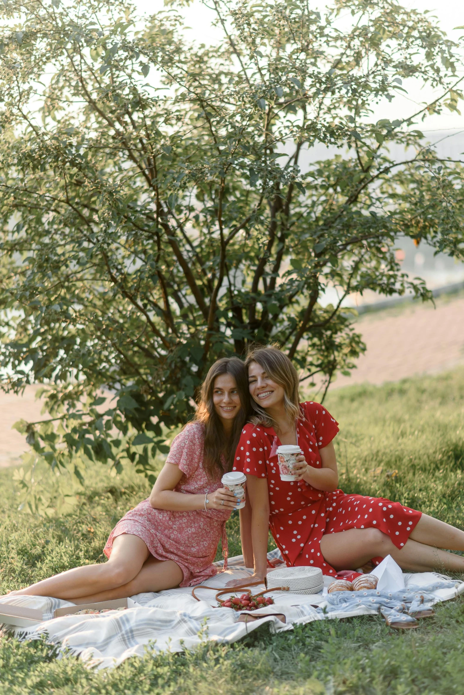 two pretty young ladies sitting on top of a field