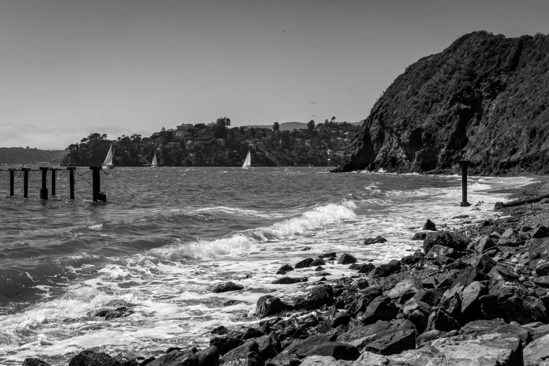 some very pretty boats in the ocean by a rocky shore