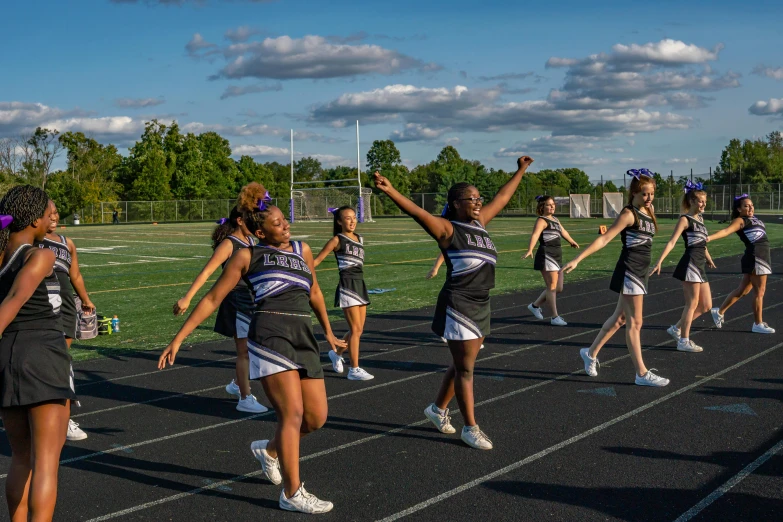 the girls in skirts are dancing together on the track