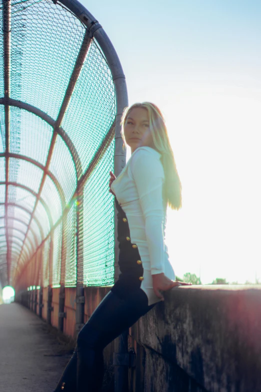 a woman leans against a railing with her hands on her hips