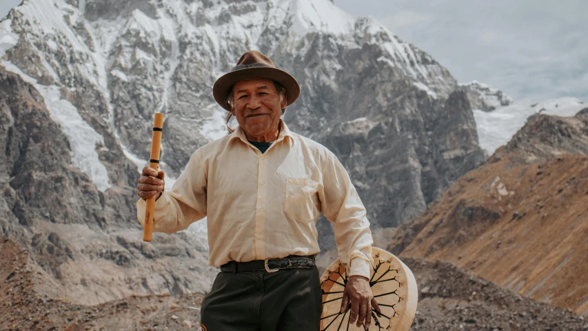 an old man with a wooden spear and an old drum