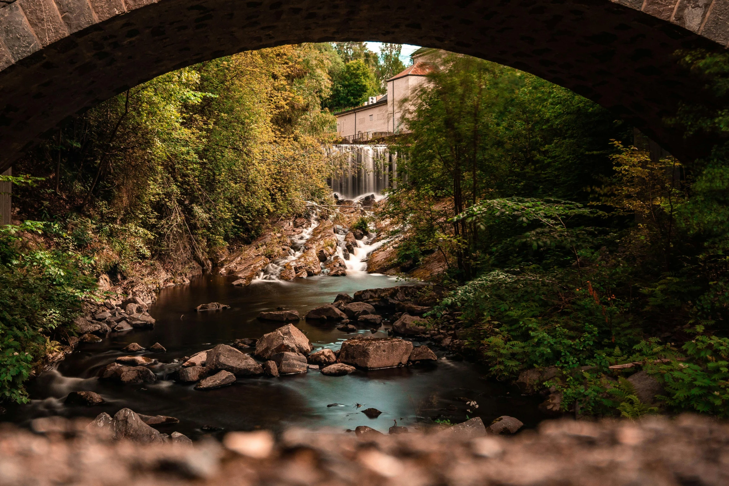 an arched stone bridge over a small river