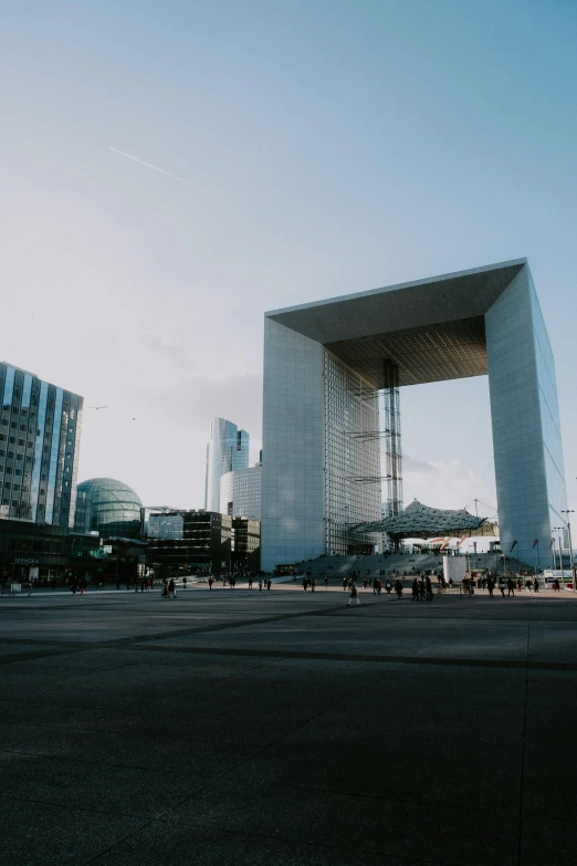 the tall and wide building is across the road from a body of water