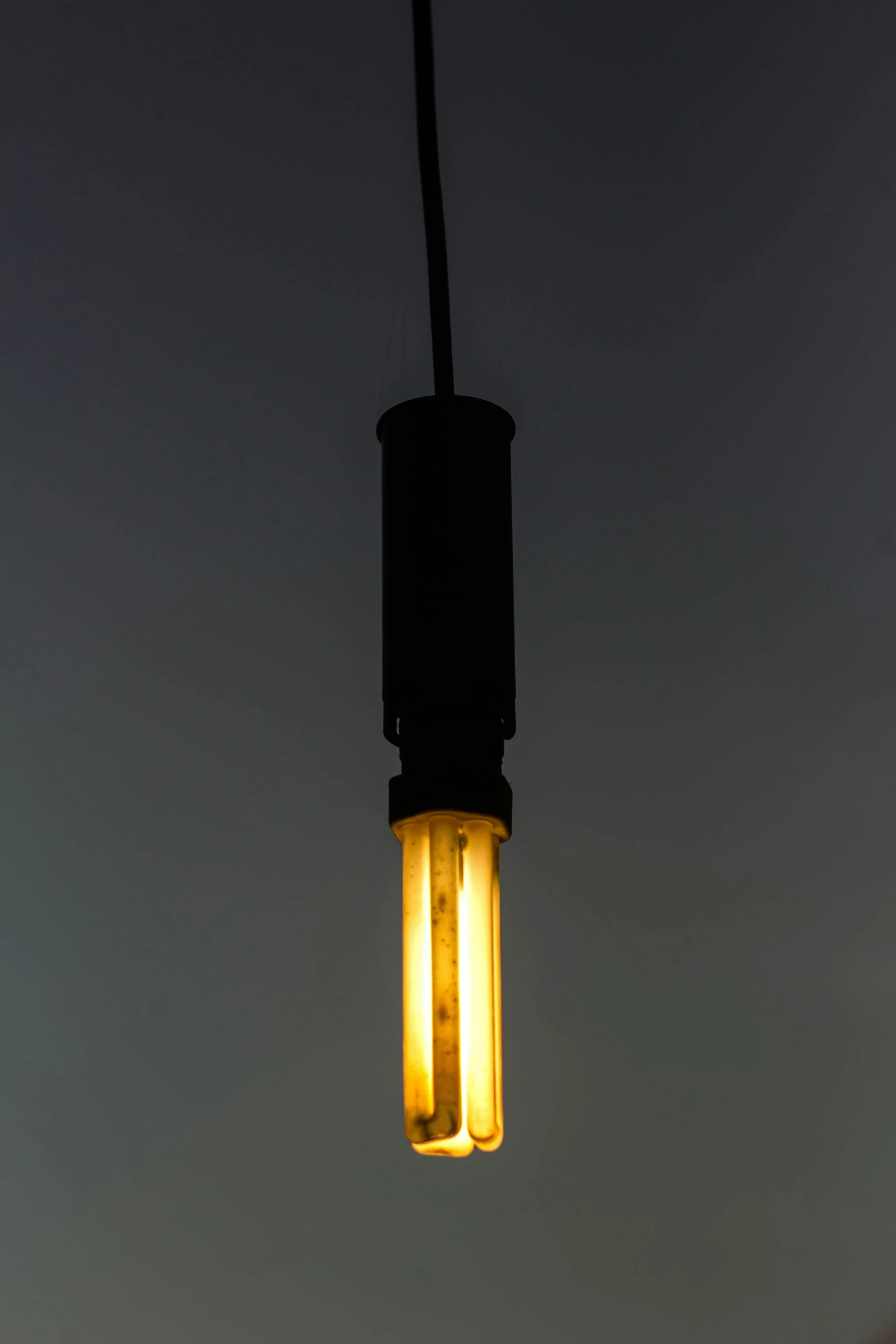 two yellow glowing lights hanging from a black wire