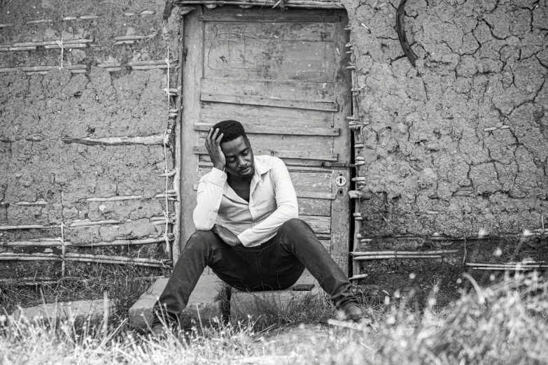 a man sitting in front of a wooden doorway