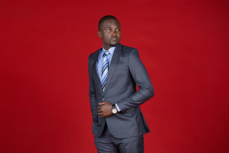 man in a grey suit standing against a red background