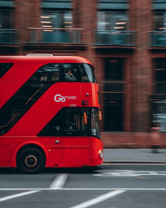 a red double decker bus driving down a street