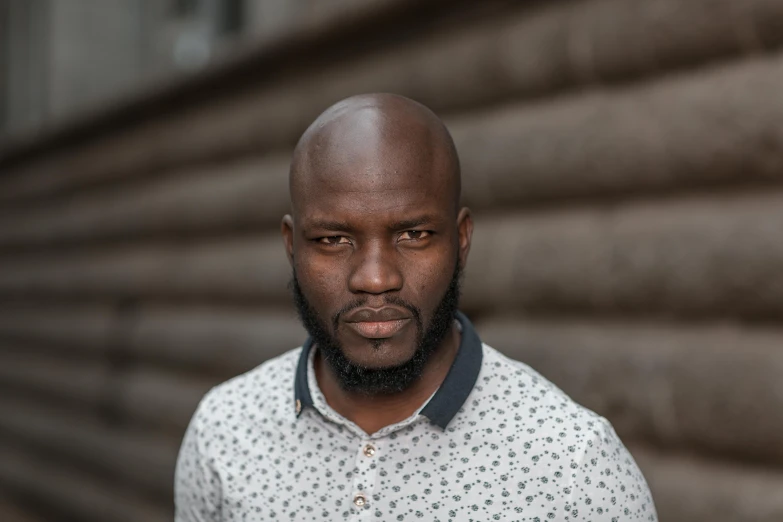 a bald man with a goatee and patterned shirt looks at the camera