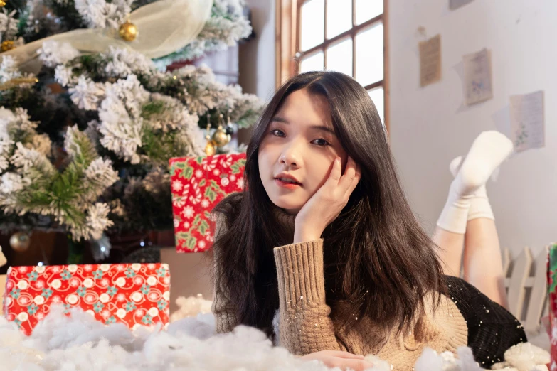 a girl sitting in front of a christmas tree