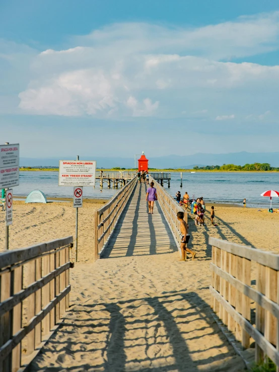 several people stand on the end of a boardwalk near a beach