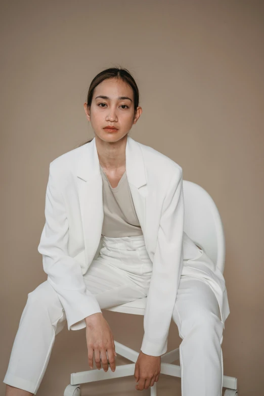 a woman in a white suit sitting on a chair