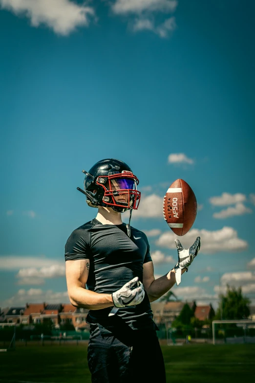 the man is posing with the football and wearing goggles