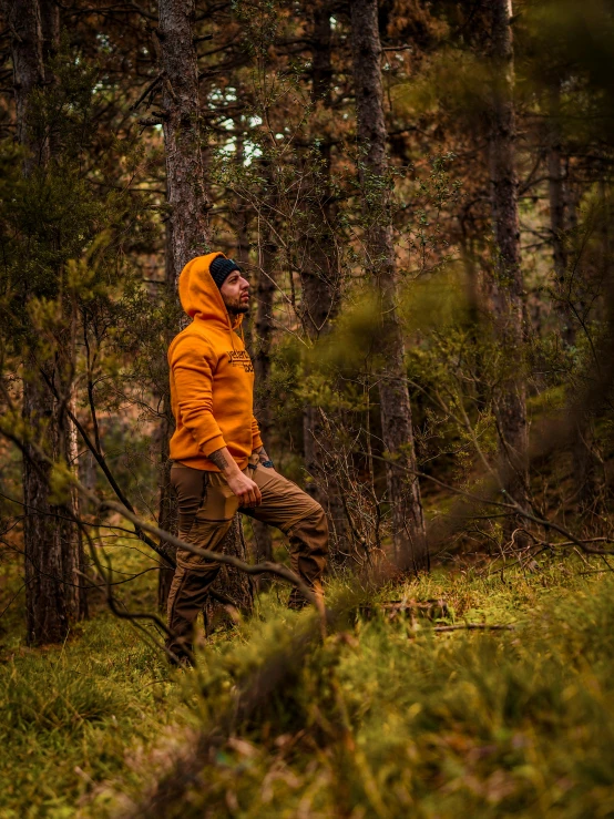 a person in orange jacket standing in a forest