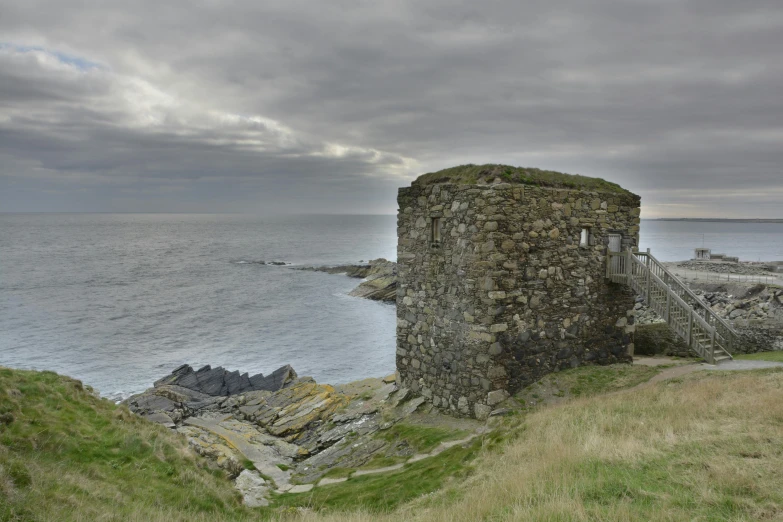 some very pretty ruins by the sea on the side of a hill