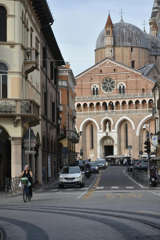 a street with lots of cars parked on either side and two people riding a bicycle