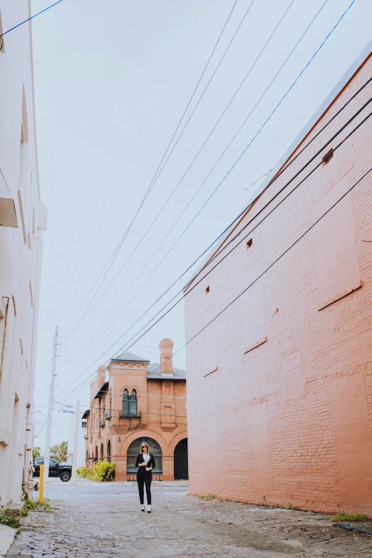 a man standing next to a pink building under power lines