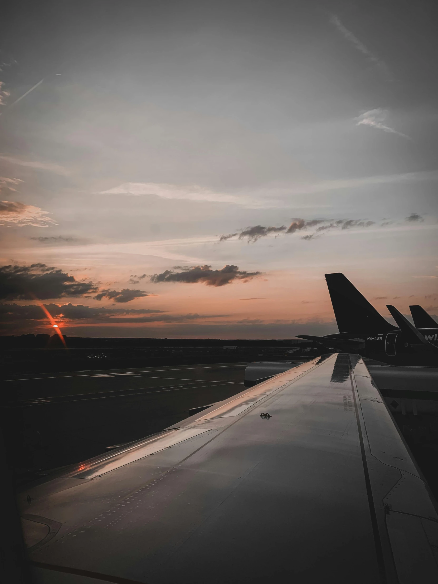 a airplane wing and some clouds at sunset