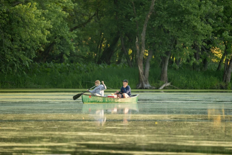 two people sitting in a small boat on a lake