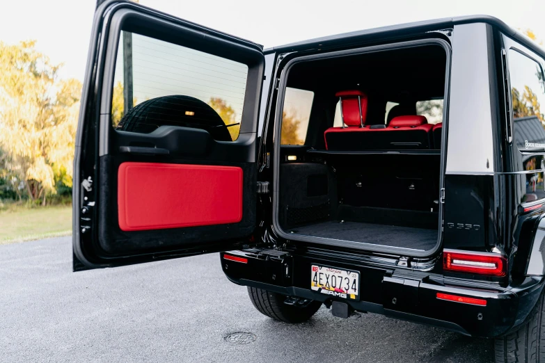 a back door opened showing luggage, a bag and a car