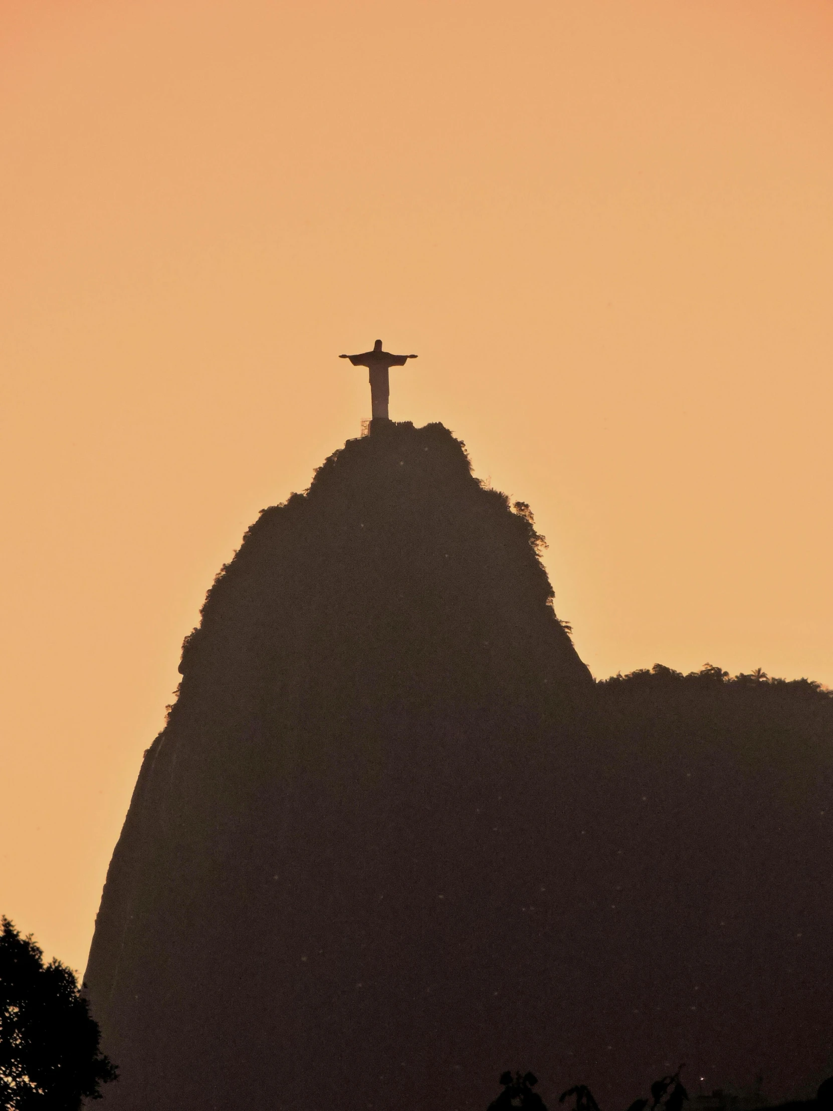 a cross is standing atop a hill above trees