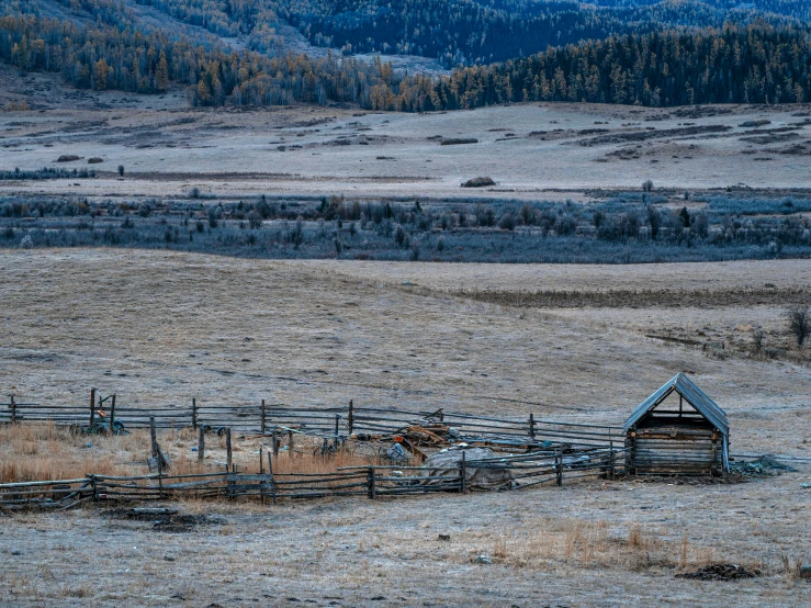 an old wooden fence in a field surrounded by mountains