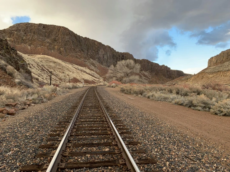 railroad tracks lead to a hill in the desert